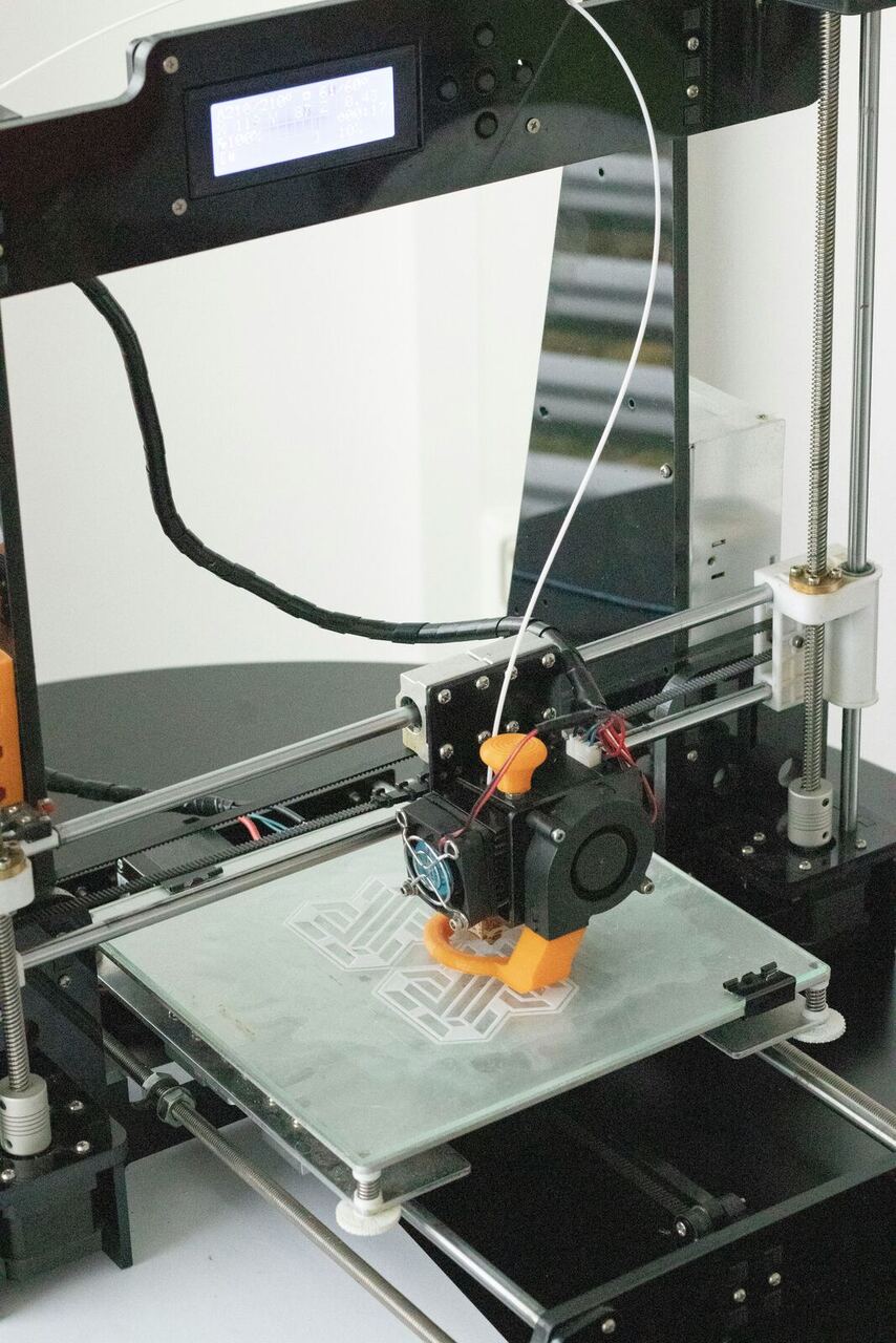 Extreme close-up of a 3D printer nozzle depositing material, representing product development support